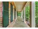 Relaxing covered porch with patterned flooring, white columns, and scenic views of the lush yard at 9257 Sauls Rd, Raleigh, NC 27603