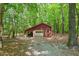 Rustic red shed with a white garage door and gravel driveway at 9257 Sauls Rd, Raleigh, NC 27603