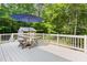 Backyard deck with white railing, umbrella-covered outdoor dining table, and surrounding wooded area at 9507 Sertoma Rd, Chapel Hill, NC 27516