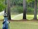 Golf bag near a pond being watered by sprinklers, set amidst tall trees on the golf course at 95113 Vance Knls, Chapel Hill, NC 27517