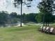 Picturesque golf course featuring sprinklers watering the green, a lake, and comfortable seating at 95113 Vance Knls, Chapel Hill, NC 27517