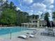 Inviting swimming pool area with lounge chairs, a building with a pergola, and lush green trees at 95113 Vance Knls, Chapel Hill, NC 27517