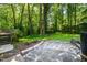 Lush backyard with stone patio, wooden steps, trees, and green grass at 1006 Apache Ln, Apex, NC 27502