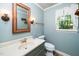 Cozy bathroom featuring blue walls, an ornate mirror, and decorative sconces at 1006 Apache Ln, Apex, NC 27502
