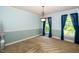Dining room featuring blue walls, carpet, large windows with dark curtains, and hanging light fixture at 1006 Apache Ln, Apex, NC 27502