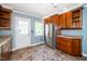Bright kitchen with wooden cabinets, stainless steel refrigerator, tile floor, and exterior door at 1006 Apache Ln, Apex, NC 27502