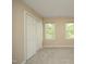 An empty bedroom space featuring tan walls, carpeted floors, a closet, and two bright windows at 105 Old Dock Trl, Cary, NC 27519
