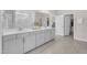 Bathroom featuring a double vanity, light gray cabinets, and wood-look floors, leading to the walk-in shower at 109 Crested Coral Dr, Holly Springs, NC 27540