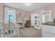 Charming Bedroom with pink walls, a crib, rocking chair, changing table, and decorative shelving at 109 Crested Coral Dr, Holly Springs, NC 27540