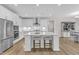 Modern eat-in kitchen with stainless appliances, white cabinets, and island with stool seating at 109 Crested Coral Dr, Holly Springs, NC 27540