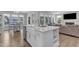 Bright kitchen features a white island with a sink, stainless steel appliances, and an open concept to the living room at 109 Crested Coral Dr, Holly Springs, NC 27540