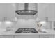 Modern kitchen features stainless steel range hood, sleek white cabinetry, and herringbone tile backsplash at 109 Crested Coral Dr, Holly Springs, NC 27540