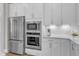 Gourmet kitchen boasts stainless steel refrigerator, microwave, and oven complemented by stylish white cabinets and countertops at 109 Crested Coral Dr, Holly Springs, NC 27540