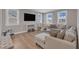 Bright living room featuring hardwood floors, large windows, and neutral furniture at 109 Crested Coral Dr, Holly Springs, NC 27540
