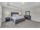 Elegant main bedroom featuring a tray ceiling, carpeted floors, and dark furniture at 109 Crested Coral Dr, Holly Springs, NC 27540