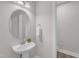 Stylish powder room featuring a pedestal sink, a round mirror, and a convenient towel holder at 109 Crested Coral Dr, Holly Springs, NC 27540