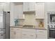 Modern kitchen boasts white cabinets, stainless steel appliances, and a stylish backsplash, blending form and function at 1161 Tulip Poplar Rd, Fuquay Varina, NC 27526