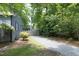 Gravel driveway leading to backyard and detached garage, lined with greenery and mature trees at 120 Pine St, Carrboro, NC 27510