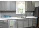 Close-up of kitchen features gray cabinetry, mosaic backsplash, and stainless steel appliances at 120 Pine St, Carrboro, NC 27510