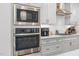 Close-up of stainless steel built-in microwave, oven, gas stovetop, and white cabinets in a modern kitchen at 1203 Corkery Ridge Ct, Cary, NC 27519