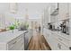 Chef's kitchen featuring white cabinetry, stainless steel appliances, a large island, and wood floors leading to dining area at 1203 Corkery Ridge Ct, Cary, NC 27519