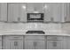 Close-up of kitchen featuring gray cabinets, stainless steel microwave and stove, and a white backsplash at 1217 Linkwood Way, Fuquay Varina, NC 27526