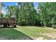 The backyard features an open lawn and large trees, as well as a wooden deck with a grill at 1304 Double Oak Ln, Willow Springs, NC 27592