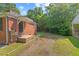 Side yard showing a brick home exterior with ample parking space and green surroundings at 1411 Hudson Ave, Durham, NC 27705