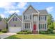 Inviting two-story home featuring gray siding, a vibrant red front door, and meticulous landscaping at 1504 Haventree Rd, Durham, NC 27713