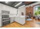 Updated kitchen with modern appliances, open layout, brick wall accent, and hardwood floors at 1535 Caraleigh Mills Ct # 210, Raleigh, NC 27603