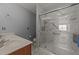 Well-lit bathroom with dual sinks and a glass-enclosed shower with modern fixtures and marble look tile at 1604 Carnation Dr, Durham, NC 27703