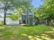 Backyard view showcasing a well-maintained lawn, a gray home exterior, and mature trees at 1605 Valley Run, Durham, NC 27707