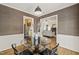 This dining room features grasscloth wallpaper, wainscoting, and views into the kitchen and living room at 1605 Valley Run, Durham, NC 27707