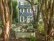 Two-story home with garden beds and lush trees surrounding, offering a serene outdoor living space at 1605 Valley Run, Durham, NC 27707