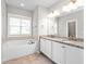 Bright bathroom featuring a soaking tub, double sink vanity with granite countertops, and natural light at 1711 Memory Ln, Burlington, NC 27217