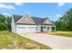 Charming home featuring a two-car garage, covered front porch, and a well-manicured lawn on a sunny day at 1711 Memory Ln, Burlington, NC 27217