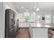 Well-lit kitchen with stainless steel appliances, white cabinetry, granite counters, and a breakfast bar at 1711 Memory Ln, Burlington, NC 27217