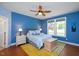 Primary bedroom with blue walls, hardwood floors, ceiling fan, and bright windows at 1724 Capstone Dr, Durham, NC 27713