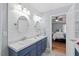 Bright bath with dual sinks, shiplap accent wall, blue vanity, and a door to the primary bedroom at 19 Knightsbridge Ct, Durham, NC 27707