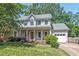 Charming two-story home with a covered front porch, lush landscaping, and an attached two-car garage at 19 Knightsbridge Ct, Durham, NC 27707