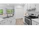 The spacious kitchen features white cabinets, stainless steel appliances, modern fixtures and wood-look floors at 19 Knightsbridge Ct, Durham, NC 27707