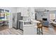 Open kitchen features white cabinets, stainless appliances, a breakfast bar with seating, and wood-look flooring at 19 Knightsbridge Ct, Durham, NC 27707