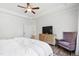 Bright bedroom featuring wood floors, ceiling fan, comfortable chair, and a dresser with a television at 1928 Vandiver Way, Apex, NC 27523