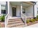 Inviting front porch with brick steps, white railings, and a modern front door adorned with a wreath at 1928 Vandiver Way, Apex, NC 27523