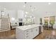 Open-concept living space featuring a bright kitchen with an island, a fireplace, and a staircase at 1928 Vandiver Way, Apex, NC 27523