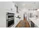 Modern kitchen with stainless steel appliances, white cabinets, and a center island overlooking the hallway at 1928 Vandiver Way, Apex, NC 27523