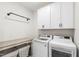 Well-organized laundry room with modern washer and dryer, storage cabinets, folding table, and convenient hanging rack at 1928 Vandiver Way, Apex, NC 27523