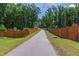 Scenic community street view with a wooden fence, trees, and a paved road, creating a welcoming entrance at 1928 Vandiver Way, Apex, NC 27523