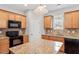 Well-lit kitchen features granite countertops, wooden cabinets and black appliances at 202 Verrazano Pl, Clayton, NC 27520
