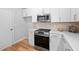 The kitchen features stainless steel appliances, white cabinets, stone countertops and a light tile backsplash at 2040 Persimmon Ridge Dr, Raleigh, NC 27604